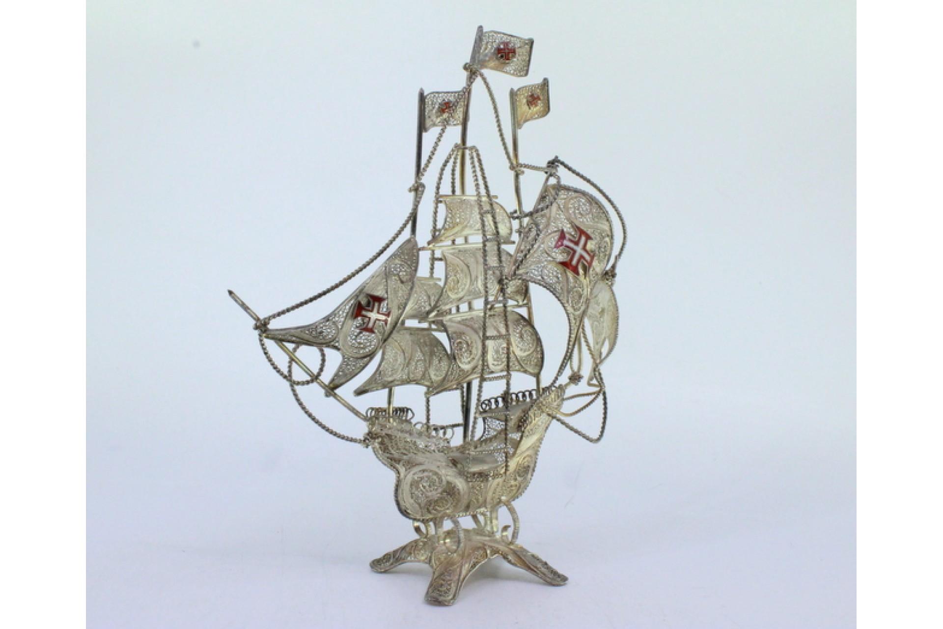 Description: Silver filigree caravel with enameled crosses on the sails and resting on a four-legged base. Metal: Silver. Origin: Portuguese. Mark: Absent. Weight: 113.22 grams. Dimensions: 17.5cm x 14.5cm. Content: 833/1000. Assay Mark: No.