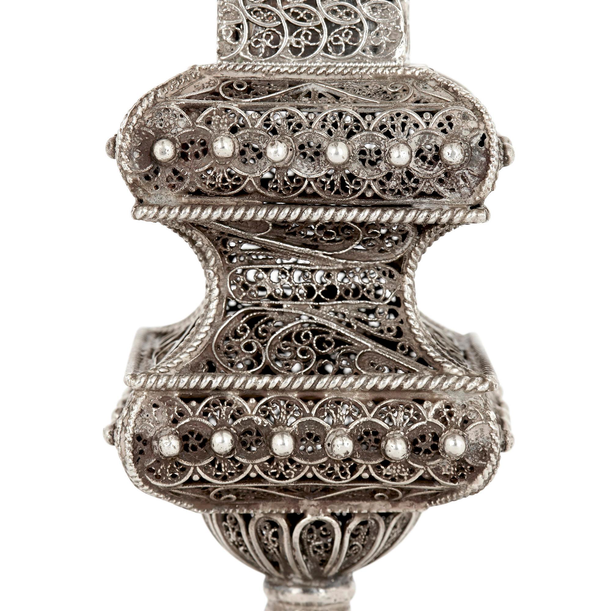The body of this large spice tower is decorated all over with fine filigree work, wrought into scrolled and geometrical designs. The tower, supported by a ball stem upon a square base, features a pinched body and a detachable pyramidal form top.