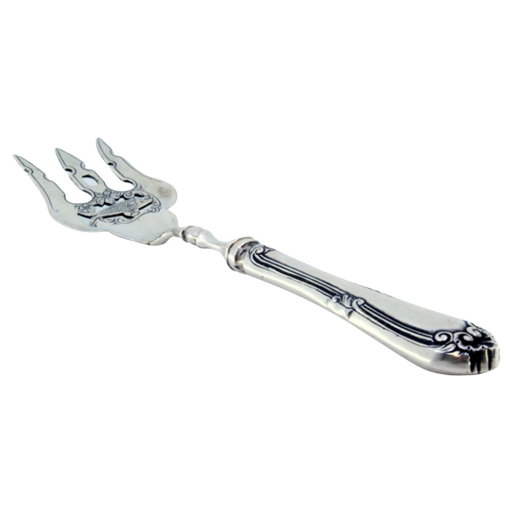 Silver fish fork with central fish figure and friezed raised handle