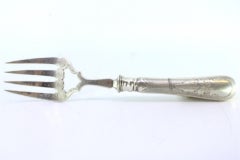 Silver fish serving fork w/ engravings surrounding a monogram card on the handle