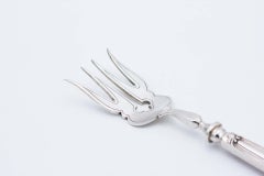 Silver fish serving fork with engravings and cutouts, relief on the shell handle