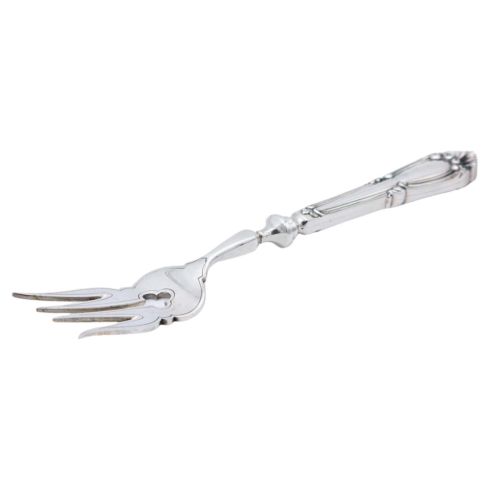 Silver fish serving fork with engravings and cutouts, relief on the shell handle
