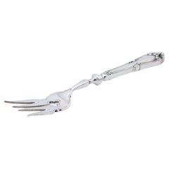 Silver fish serving fork with engravings and cutouts, relief on the shell handle