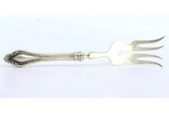 Silver fish serving fork with four tines and grooves along the raised handle