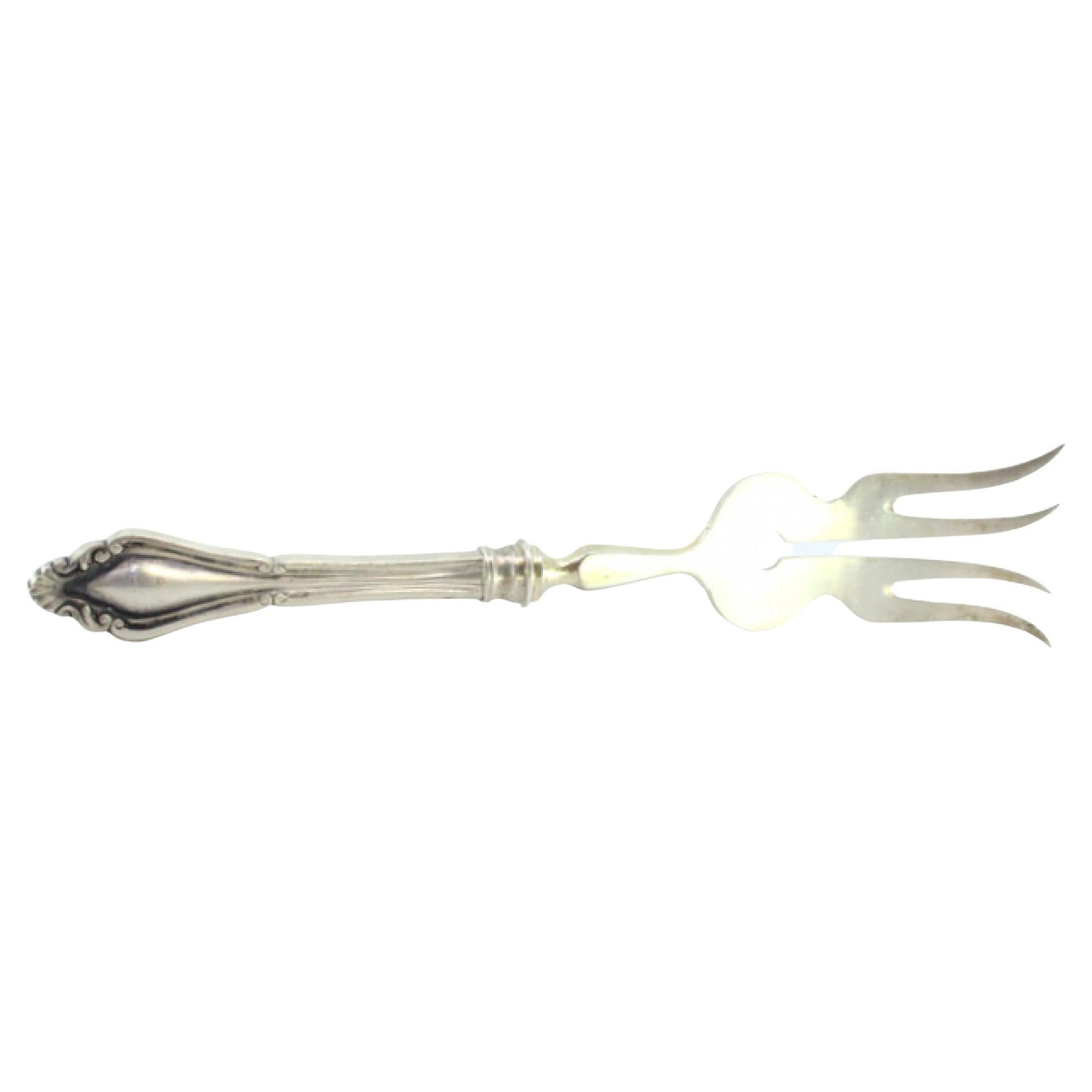 Silver fish serving fork with four tines and grooves along the raised handle