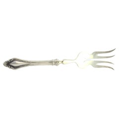 Silver fish serving fork with four tines and grooves along the raised handle