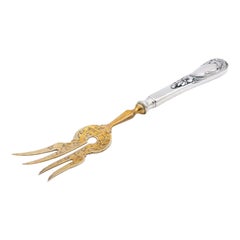 Silver fish serving fork with gold tines and relief on the handle