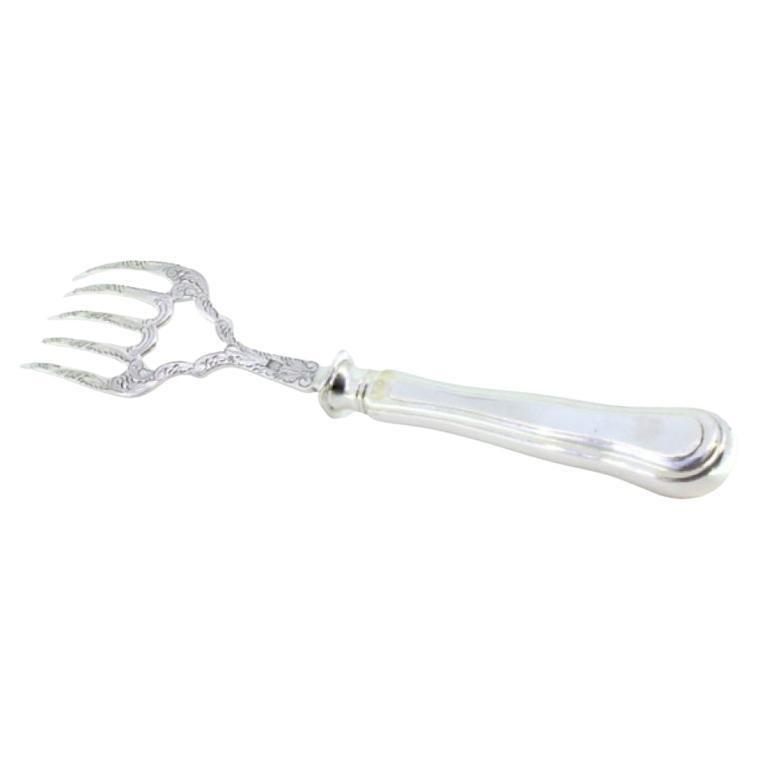Silver fish serving fork with reliefs and a crown on the handle