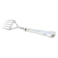 Fourchette de service à poisson en argent avec des reliefs et une couronne sur le manche.