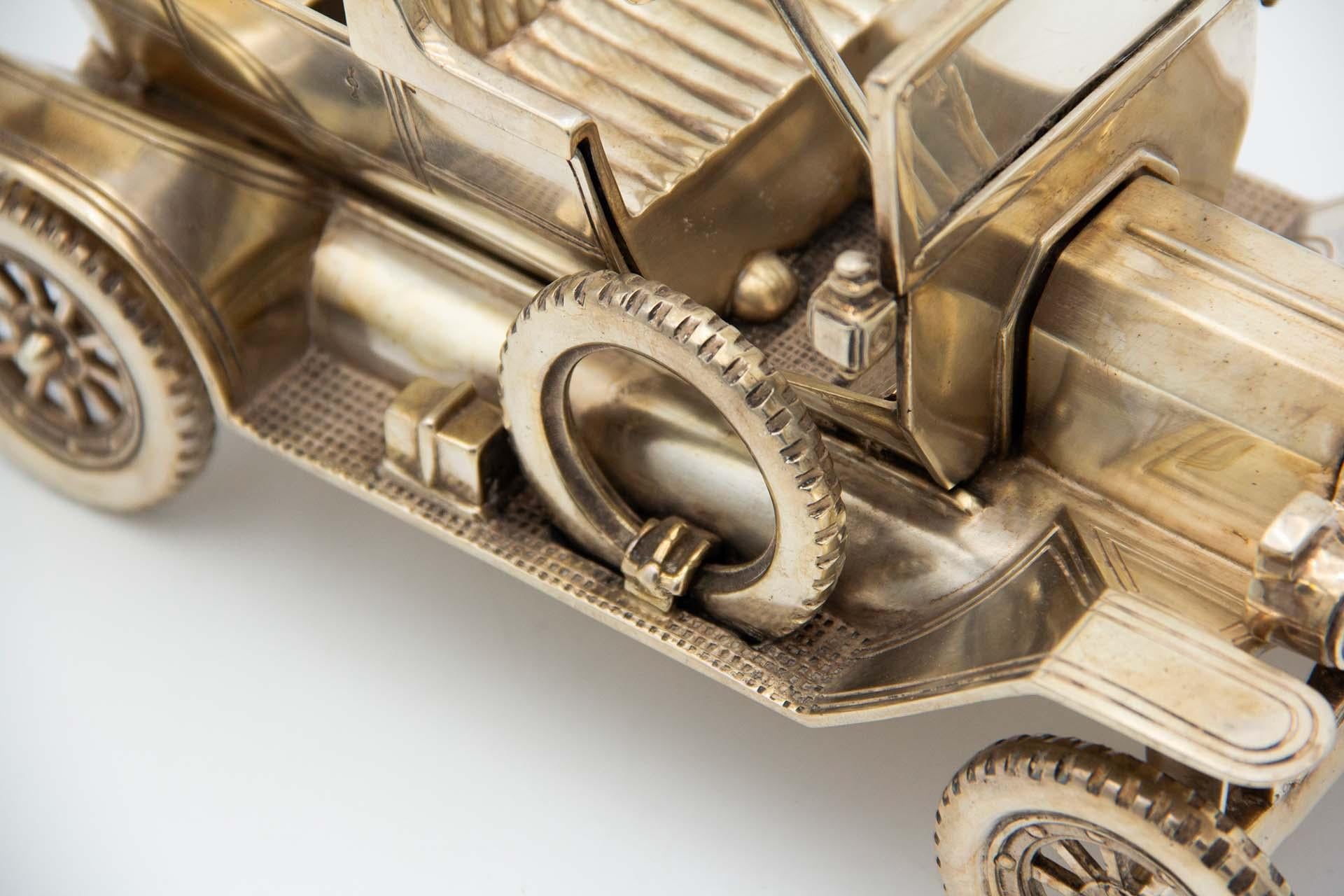 Description : Voiture décapotable Ford argentée des années 1920. Métal : Argent. Origine : Portugais. Poinçon : aigle debout. Poids : 2247,55 grammes. Dimensions : 22.8cmx12cm : 22.8cmx12cm. Contenu : 833/1000. Marque d'essai : oui. Informations