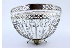 Silver fruit basket with wire rack, hinged handle and four leaf-scroll feet