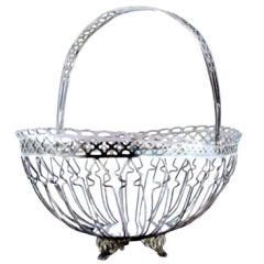 Silver fruit basket with wire rack, hinged handle and four leaf-scroll feet