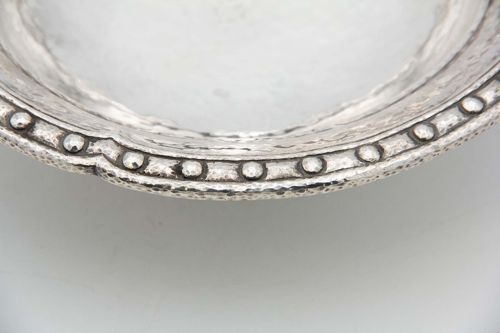 Description: Fruit bowl centerpiece in hammered silver with pearly rim. Metal: Silver. Origin: Portuguese. Mark: standing eagle - I Title. Weight: 842.23 grams. Dimensions: 24.7cmx7.3cm. Content: 916/1000. Assay Mark: Yes, between 1938 and 1984.