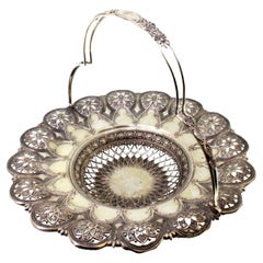 Silver fruit bowl with cutouts, floral embossing and hinged monogram handle