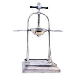 Silver fruit juicer with two side supports with floral motifs and a wooden base