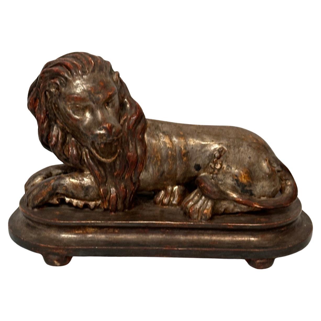 Escultura de león reclinado de plata dorada