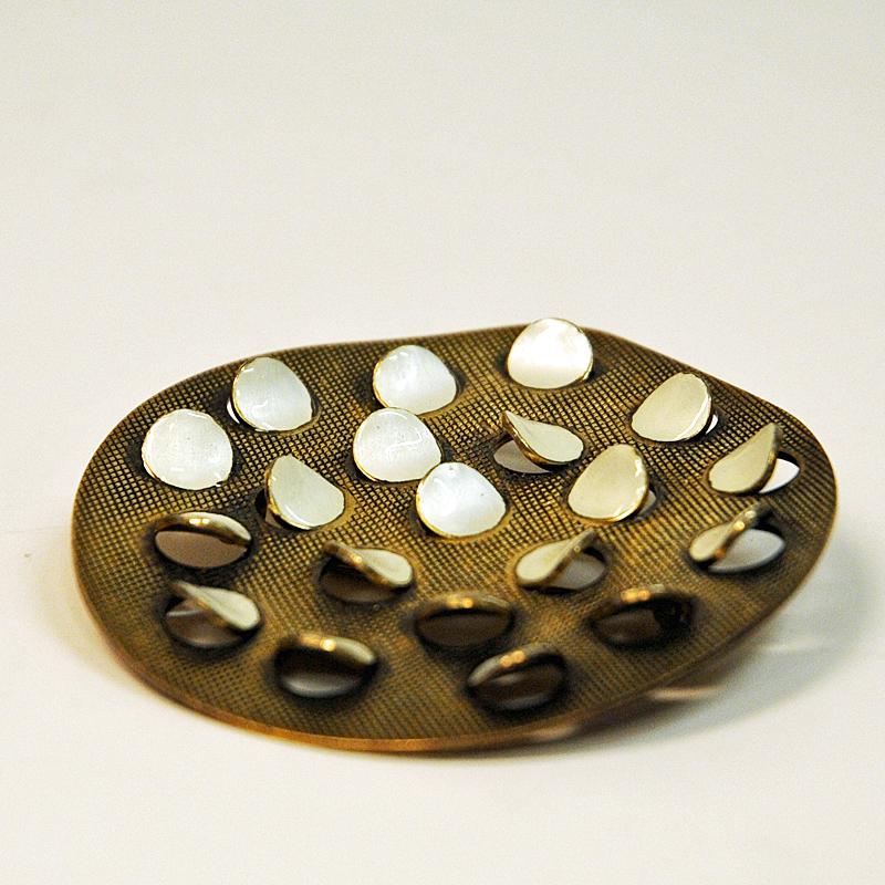 Midcentury silver gilt broch with offwhite enameled flaps or spots on the surface by designer Grete Prytz Kittelsen for J.Tostrup, Norway 1950s. Stamped ‘Tostrup‘, ‘Sterling’ and ‘Norway’ on back.
Measure: 6 cmD x 5.5 cmD. 0.5 cmT.

Grete Prytz