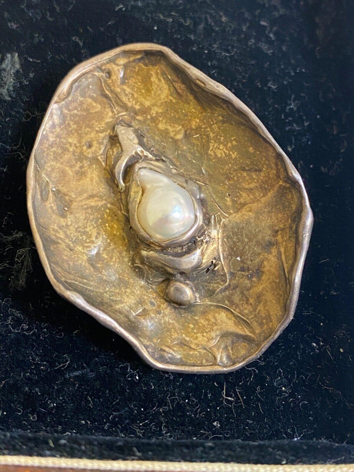 Fabriqué par le célèbre joaillier de Melbourne 
Marylyn Verstraeten

Conçu comme un mollusque (où se forme la perle), 
légèrement déformé et mesurant 45 mm x 32 mm 
la broche est réalisée en argent sterling, 
avec façade en argent doré 

sertie