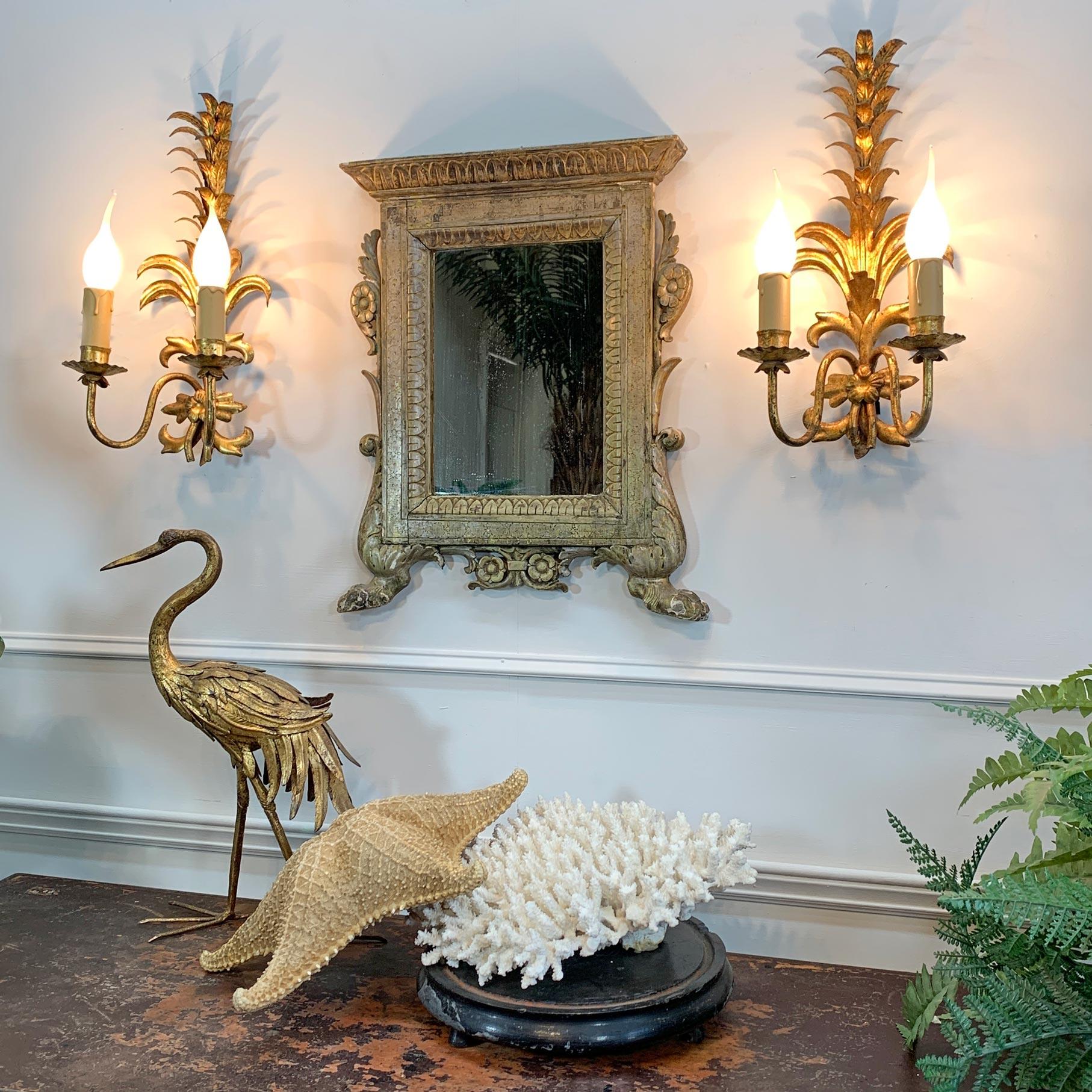 Miroir mural baroque italien du XVIIIe siècle, doré à l'argent. Le cadre en bois sculpté est orné de fleurs et de feuillages, les pieds sont en forme de pattes de lion, recouverts de gesso puis dorés à l'argent. Plaque miroir légèrement