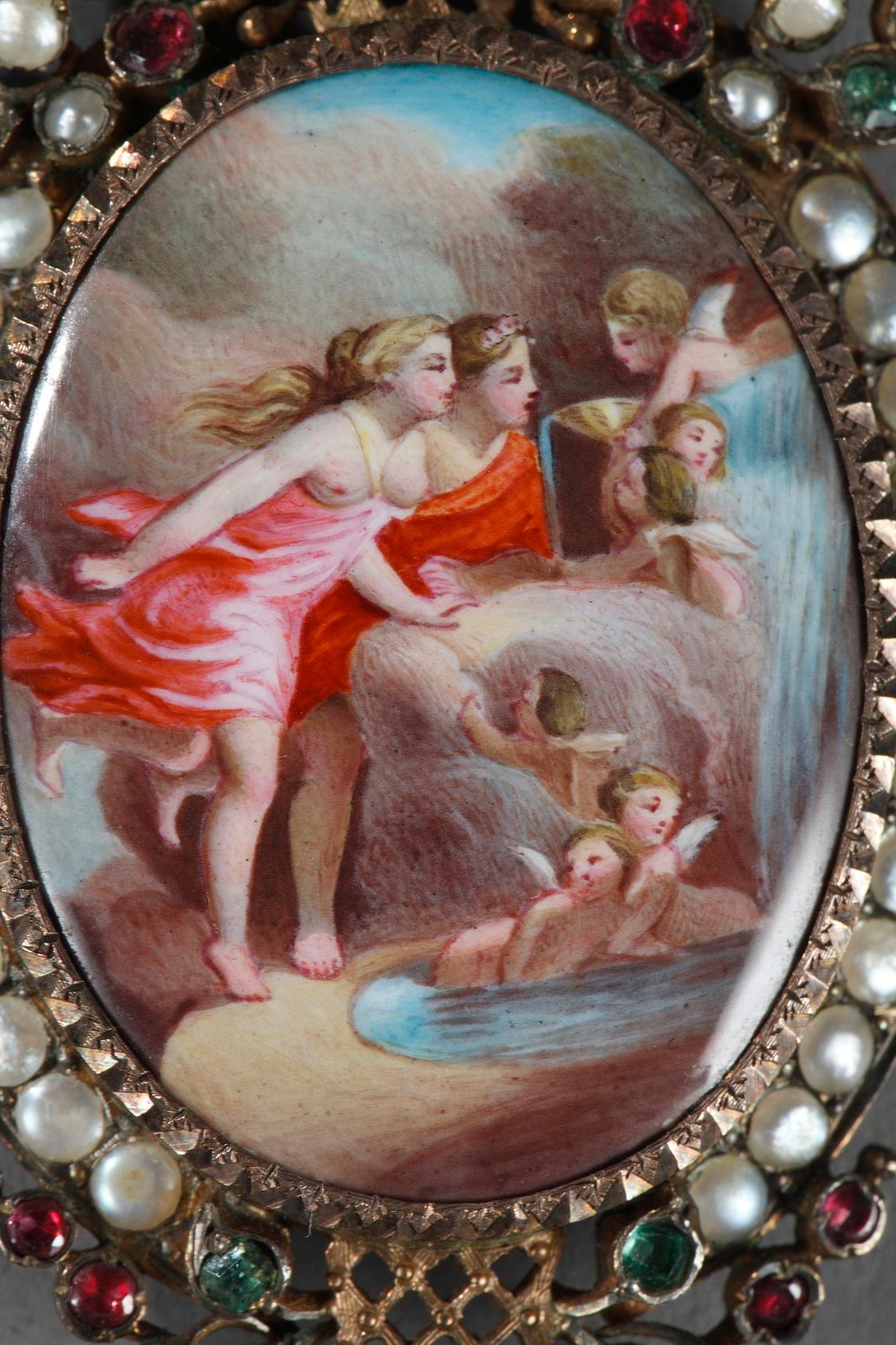 Silver-gilt pendant featuring a mythological scene on enamel representing La Fontaine de l’Amour (The Fountain of Love) after Jean-Honoré Fragonard. The setting is meticulously executed, embellished with delicate pearls, rubies, and emeralds that