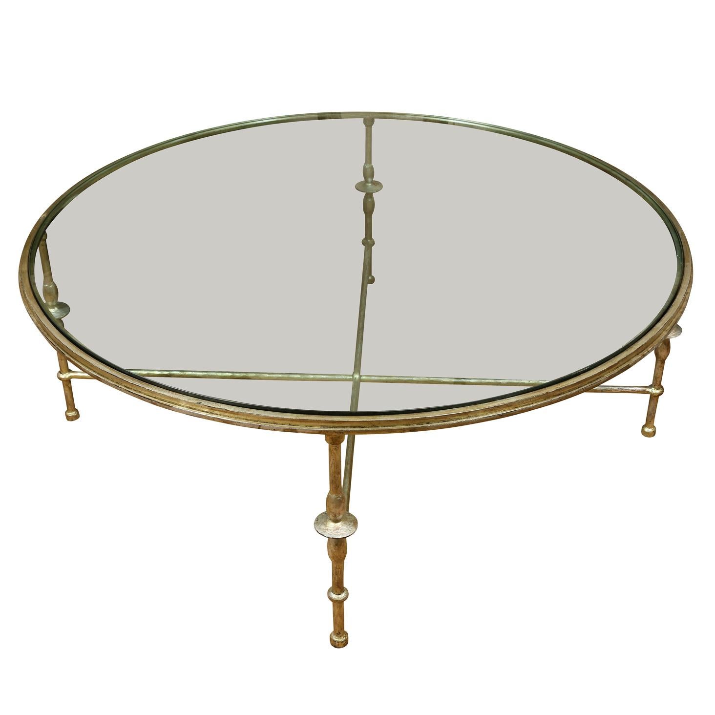 A round glass top table with silver gilt Giacometti style frame and X shaped base