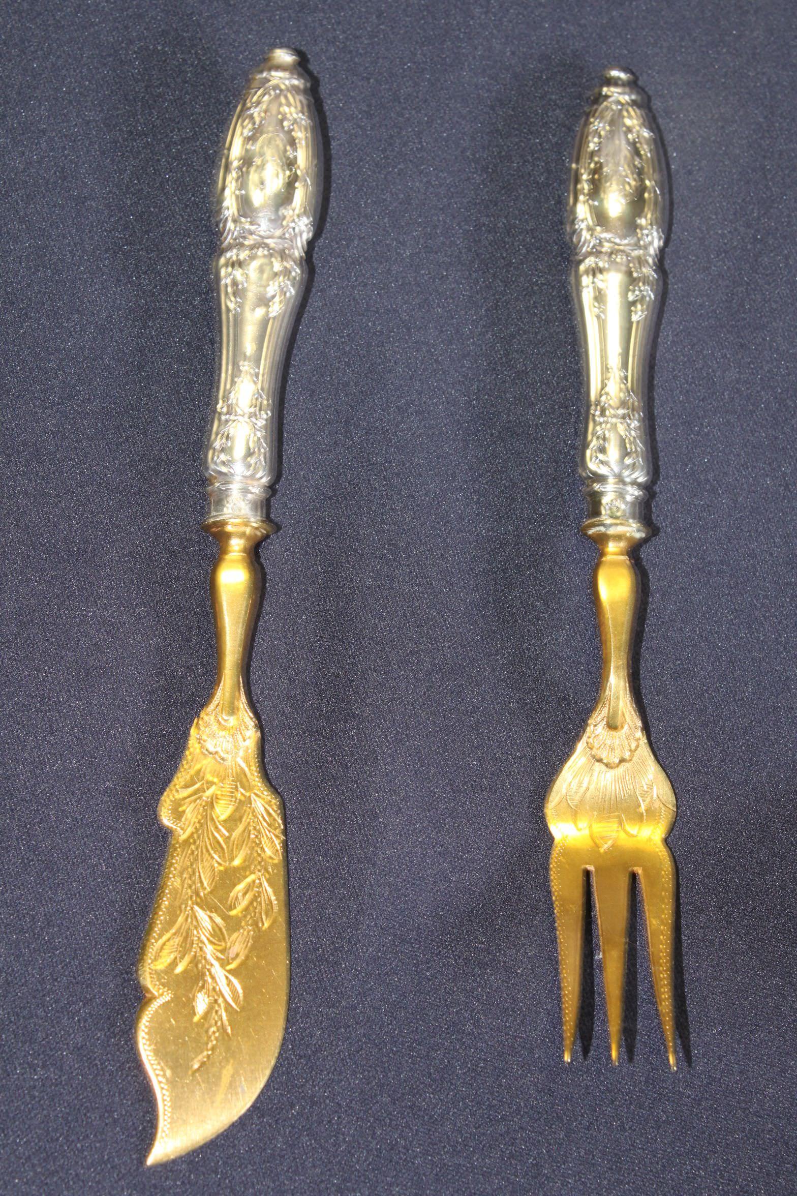This good quality silver gilt hors d'oeuvres set consists of a sardine fork, a butter knife, a pate server and an olive spoon. The silver handles are embossed with neo-classical wreaths and the blades have been engraved prior to gilding. Each of the