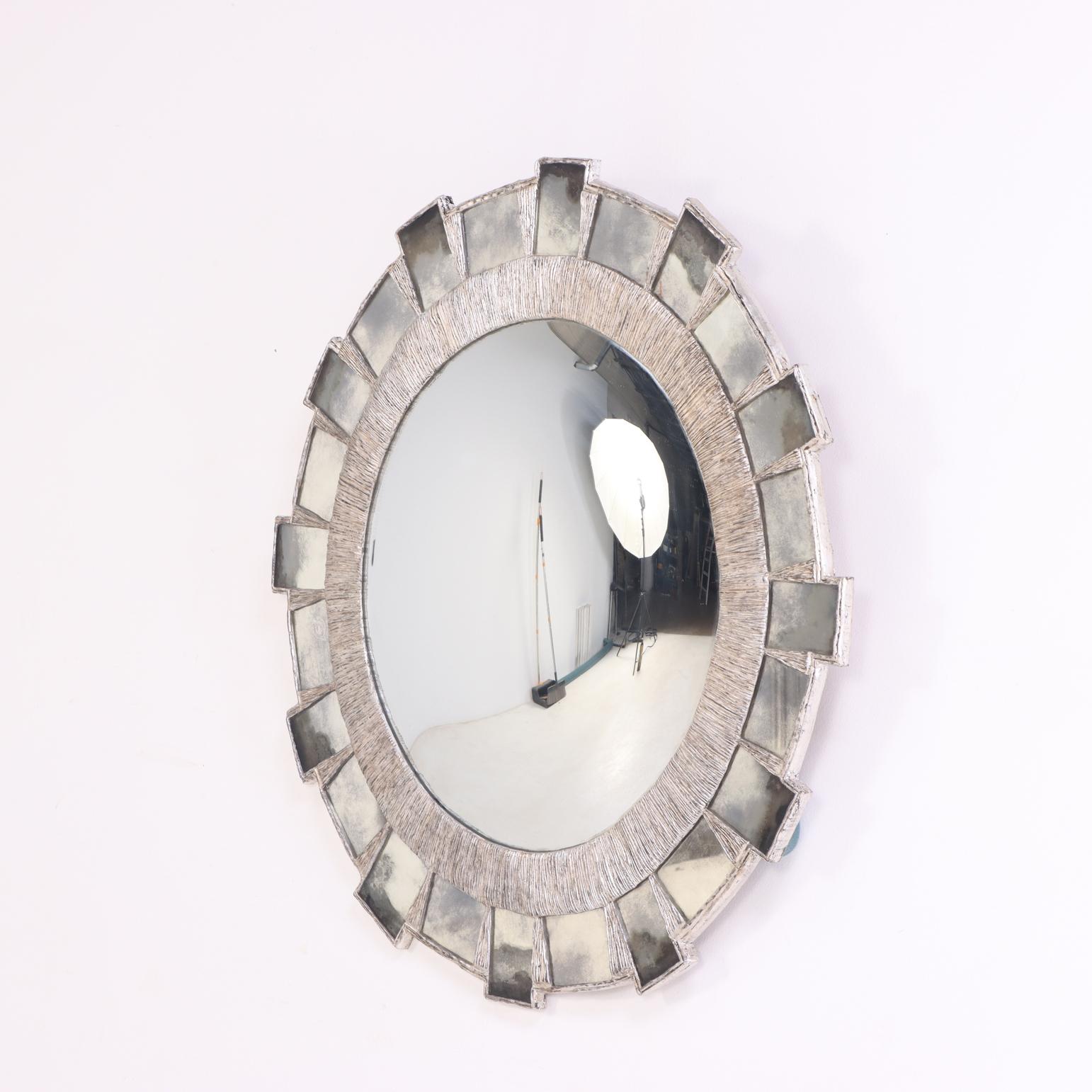 Con un diametro di 36,5 pollici, questo pezzo scultoreo presenta una composizione a raggiera di segmenti di vetro vintage a foglie d'argento incastonati in una cornice di resina argentata e dorata modellata a mano, formando un'esplosione geometrica