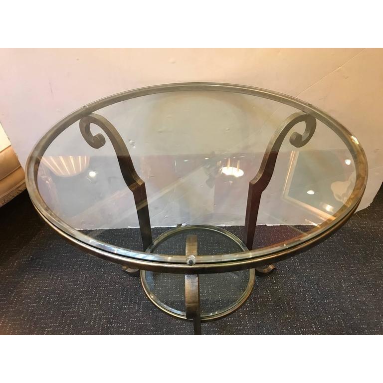 Chic silver gilt glass top table having three scrolled legs with beveled glass top and lower shelf. The table is in the manner of Barbara Barry, and gives a modern look to a classic style.