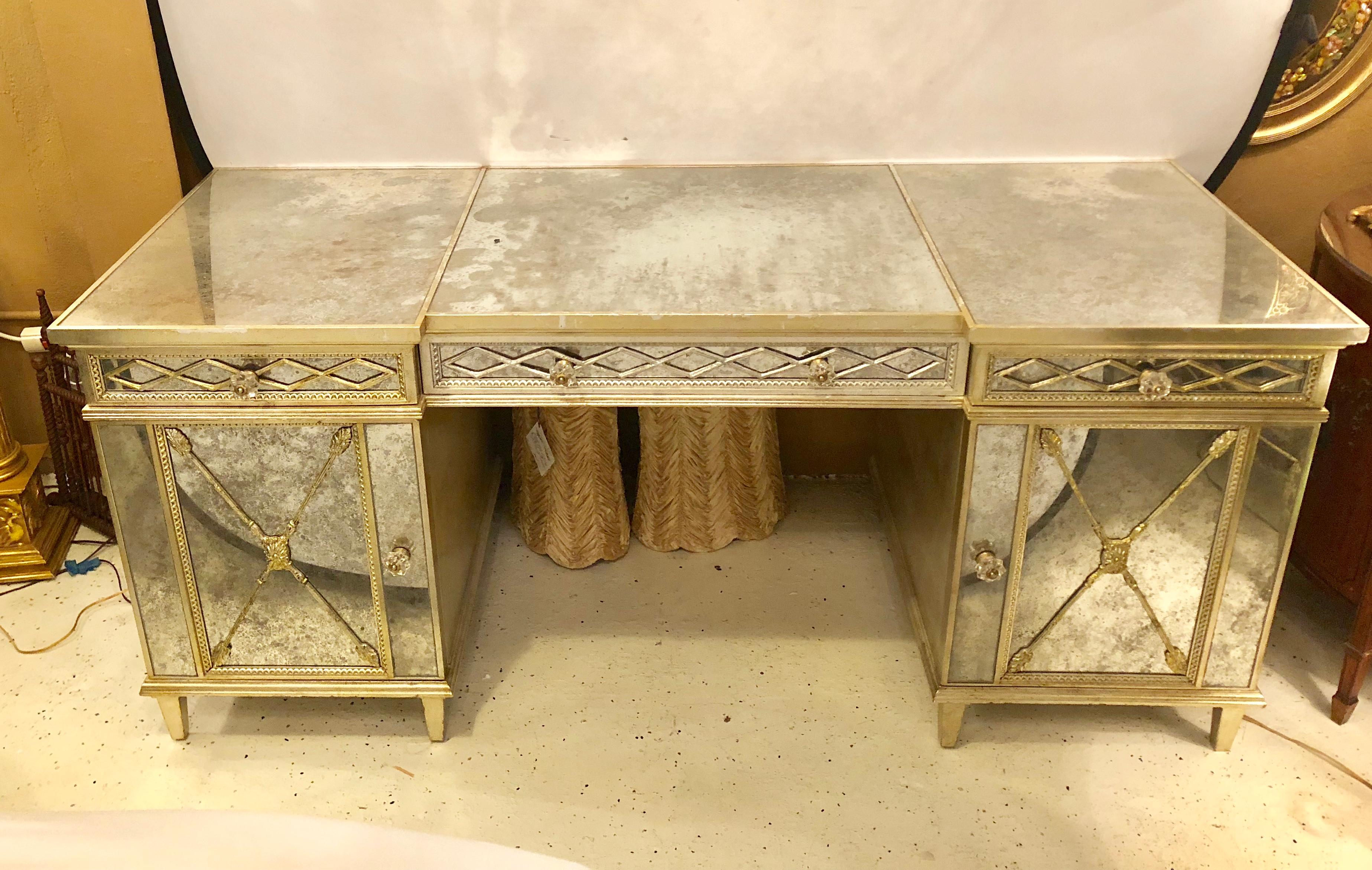 Silver gilt triple vanity with antique mirror paneling and closed arrow design. This recent palatial desk or vanity is simply stunning and certain to add great reflection to any Hollywood Regency setting. The large and deep centre drawer under a