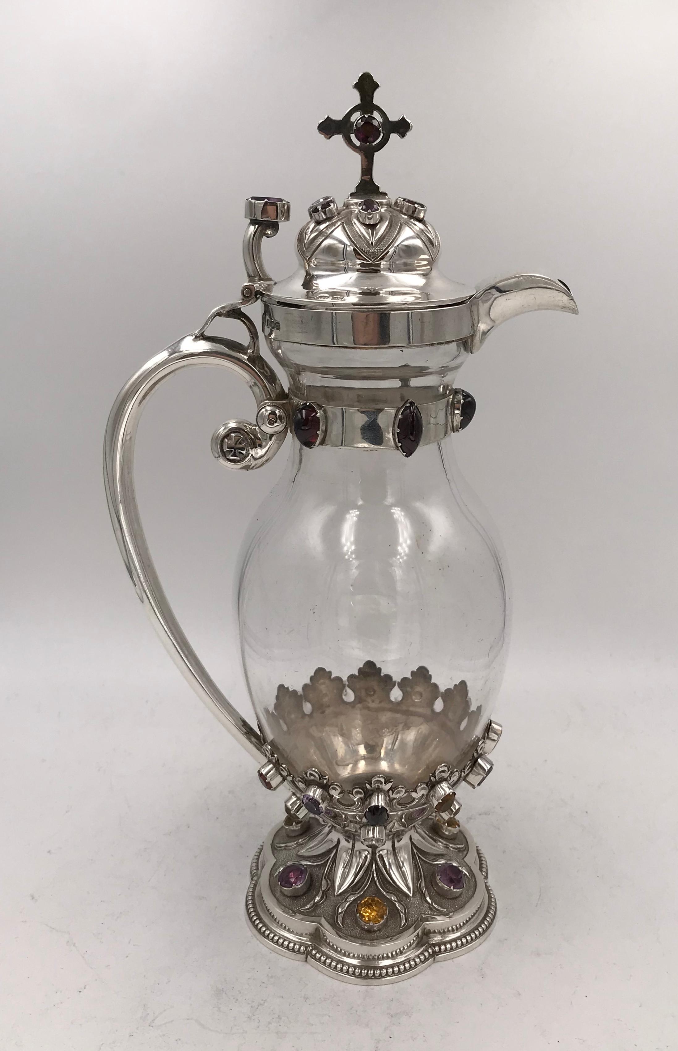 An Edwardian sterling silver mounted ecclesiastical wine jug, Sheffield 1904 by John Round & Son Ltd.
Clear glass ovoid body with hallmarked silver mounts, the hexafoil foot with beaded rim and chased decoration and adorned with collet set colored