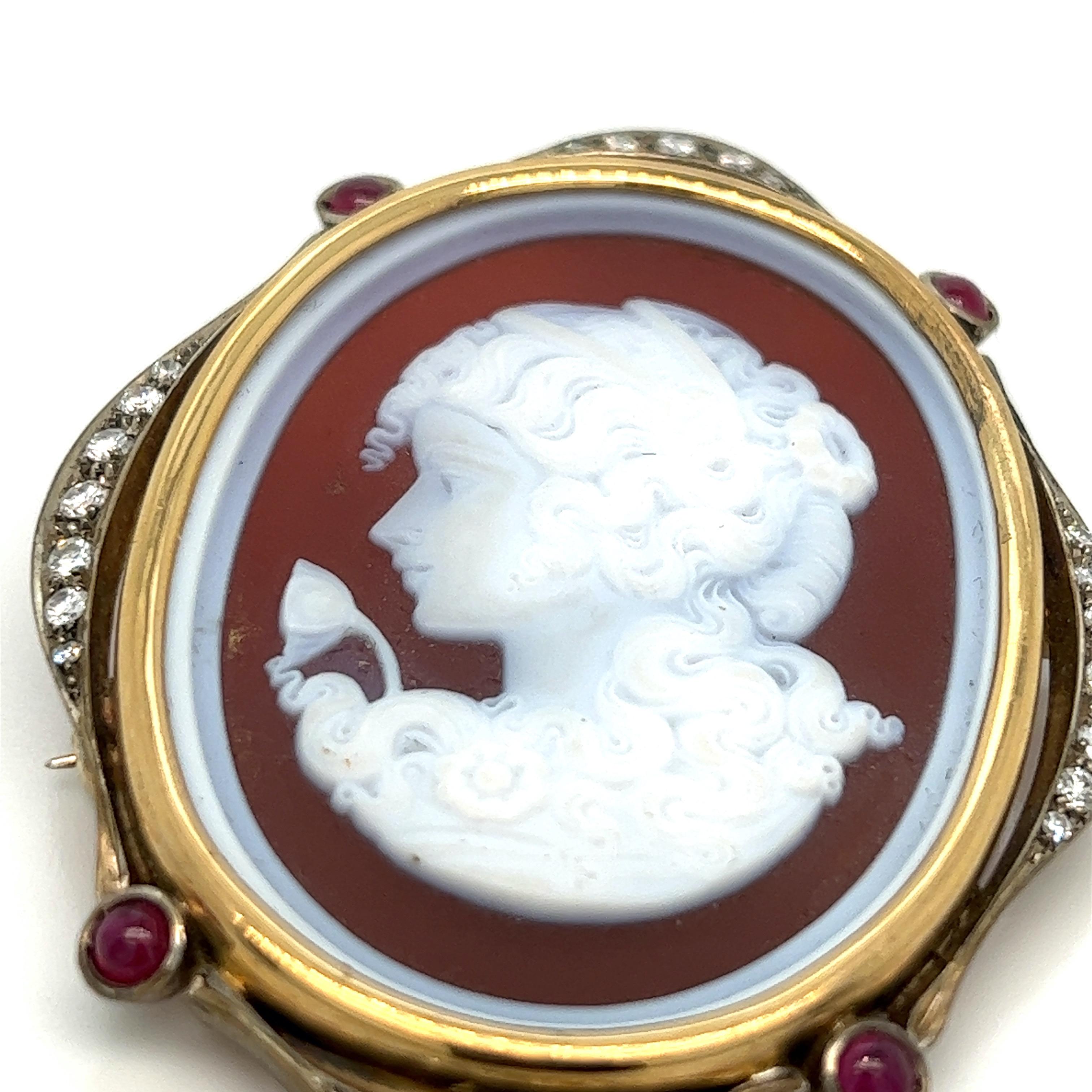 Silver and gold diamond ruby shell cameo, featuring a side profile of a Victorian lady

18 karat yellow gold, round-cut diamond of approximately 0.70 carat, cabochon rubies of approximately 0.64 carat

Size: width 1.88 inches, length 2.38