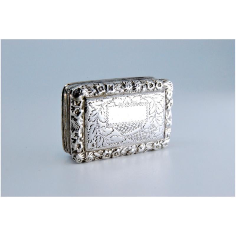 Beschreibung: Vinaigrette-Dose aus Silber und Gold mit buchförmiger Gravur aus der Zeit Georgs IV. Metall: Silber - Gold. Herkunft: Englisch. Marke: Birmingham. Gewicht: 13,74 Gramm. Abmessungen: 3,4x0,9 cm. Inhalt: Silber (925/1000) - Gold