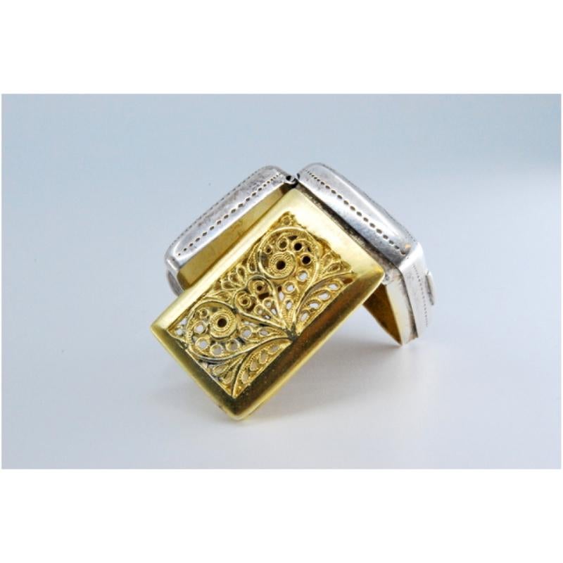 Description: Silver and gold vinaigrette box with George IV period engraving on the lid. Metal: Silver - Gold. Origin: English. Brand: Birmingham. Weight: 10.76 grams. Dimensions: 2.5x0.9cm. Content: Silver (925/1000) - Gold (375/1000). Assay Mark: