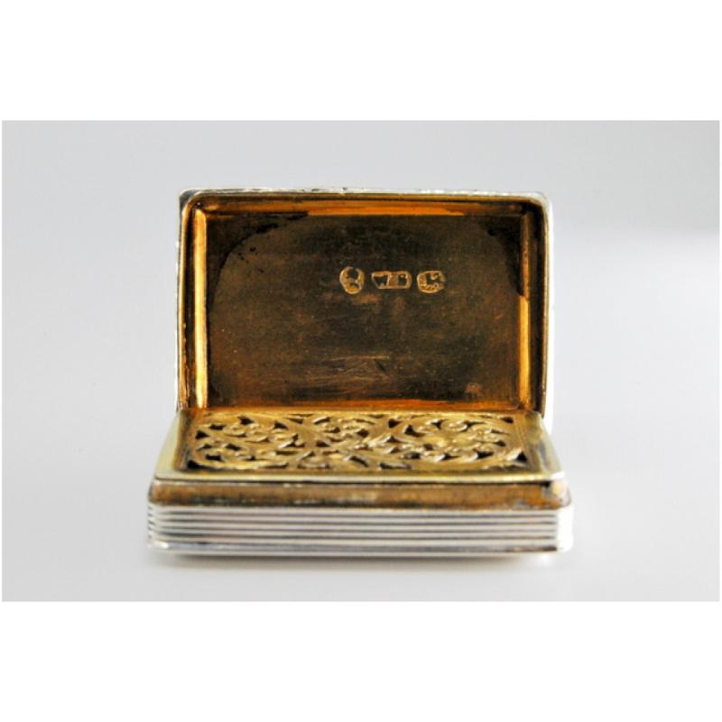 Beschreibung: Vinaigrette-Dose aus Silber und Gold mit Friesen am Rand und erhöhtem Deckel aus der Zeit Georgs IV. Metall: Silber - Gold. Herkunft: Englisch. Marke: Birmingham. Gewicht: 21,94 Gramm. Abmessungen: 3,7x1cm. Inhalt: 925/1000 (Silber) -