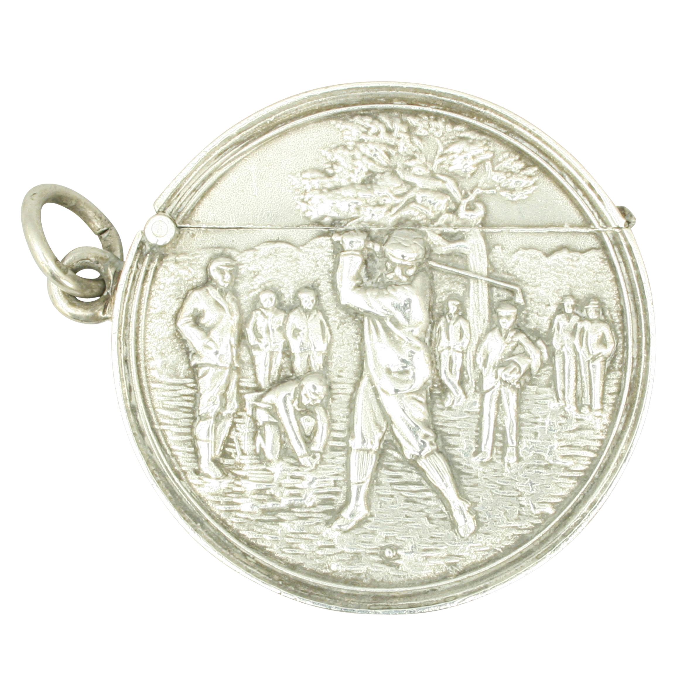 Golf Vesta case
A round antique silver golfing match safe with striker on the bottom. The match holder is embossed with a golfing scene of a male golfer in his back swing watched by eight other golfers to the front, engraved on the rear 'Won by