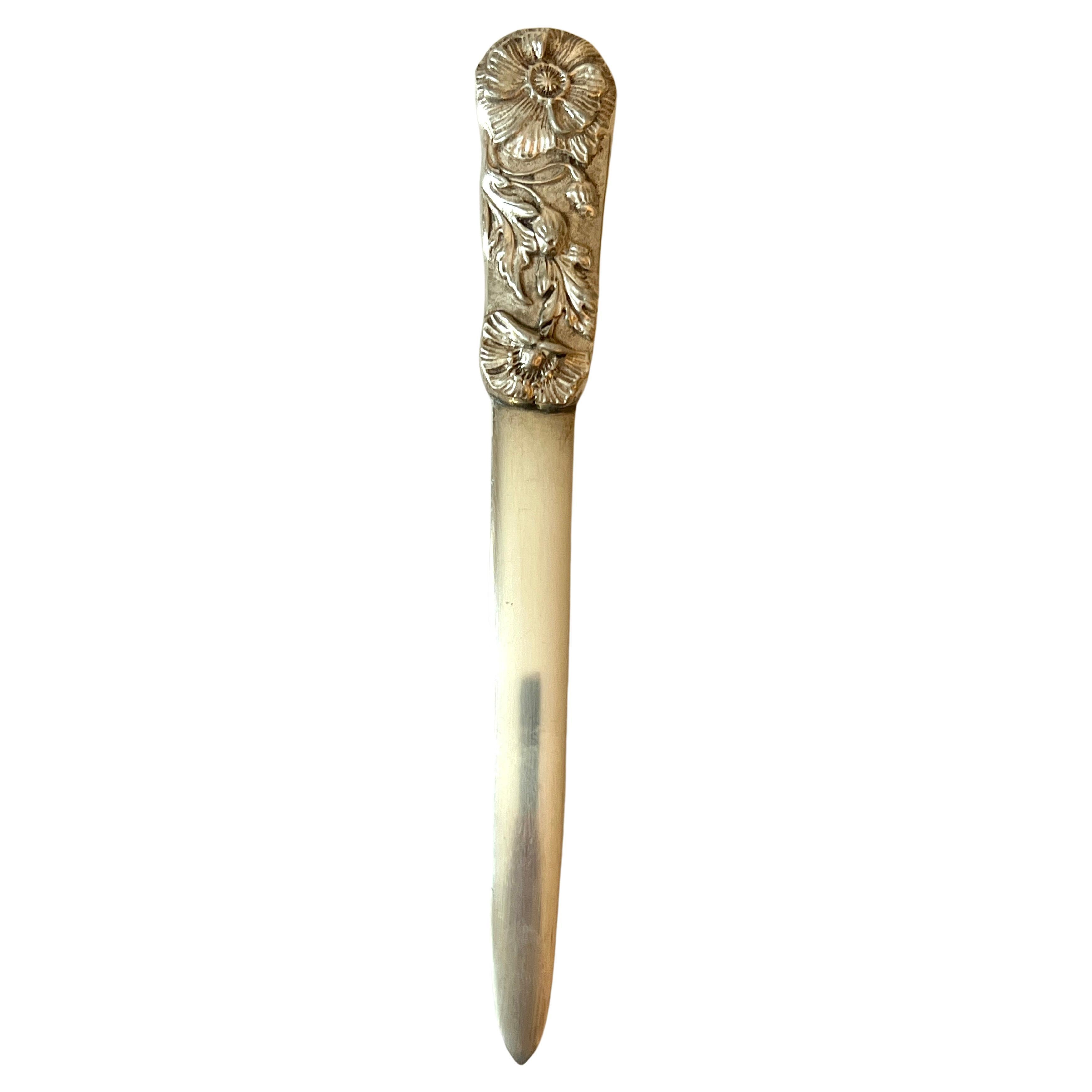 A beautiful Gotham Silver letter opener with graceful flowers and vines trailing on the handle.  A lovely piece.  Perfectly suited for any desk, work station, and definitely to make a peaceful statement about the desk which it rests upon.

We have