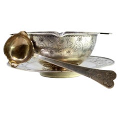 Silver gravy boat with floral motifs engraved on the plate, cup and spoon