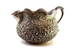 Silver gravy boat with raised floral and plant motifs, wavy rim in Arabic style