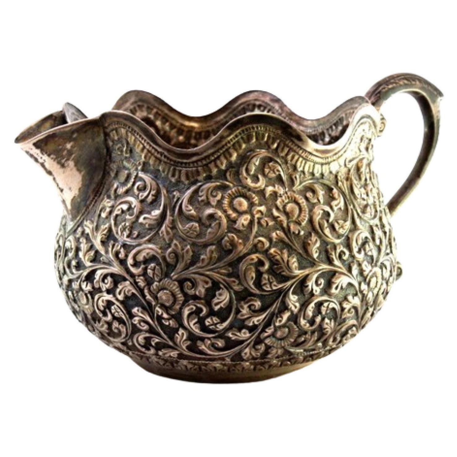 Silver gravy boat with raised floral and plant motifs, wavy rim in Arabic style