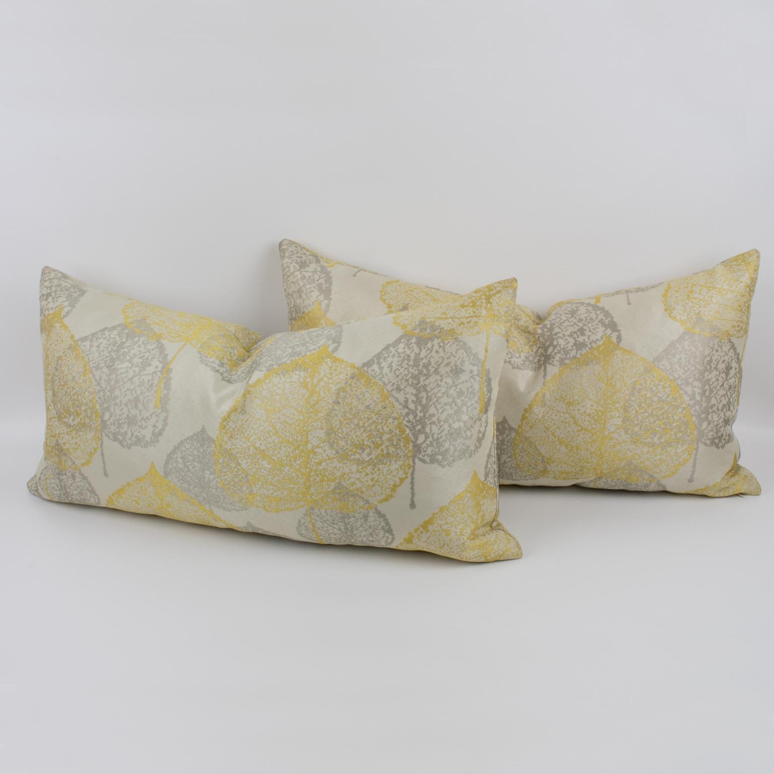 This is a lovely set of two damask throw pillows. These lumbar pillows are covered with a textured naturalist design in silver-gray and light yellow colors over a silky off-white background. A zipper encloses an inner feather pillow. Their