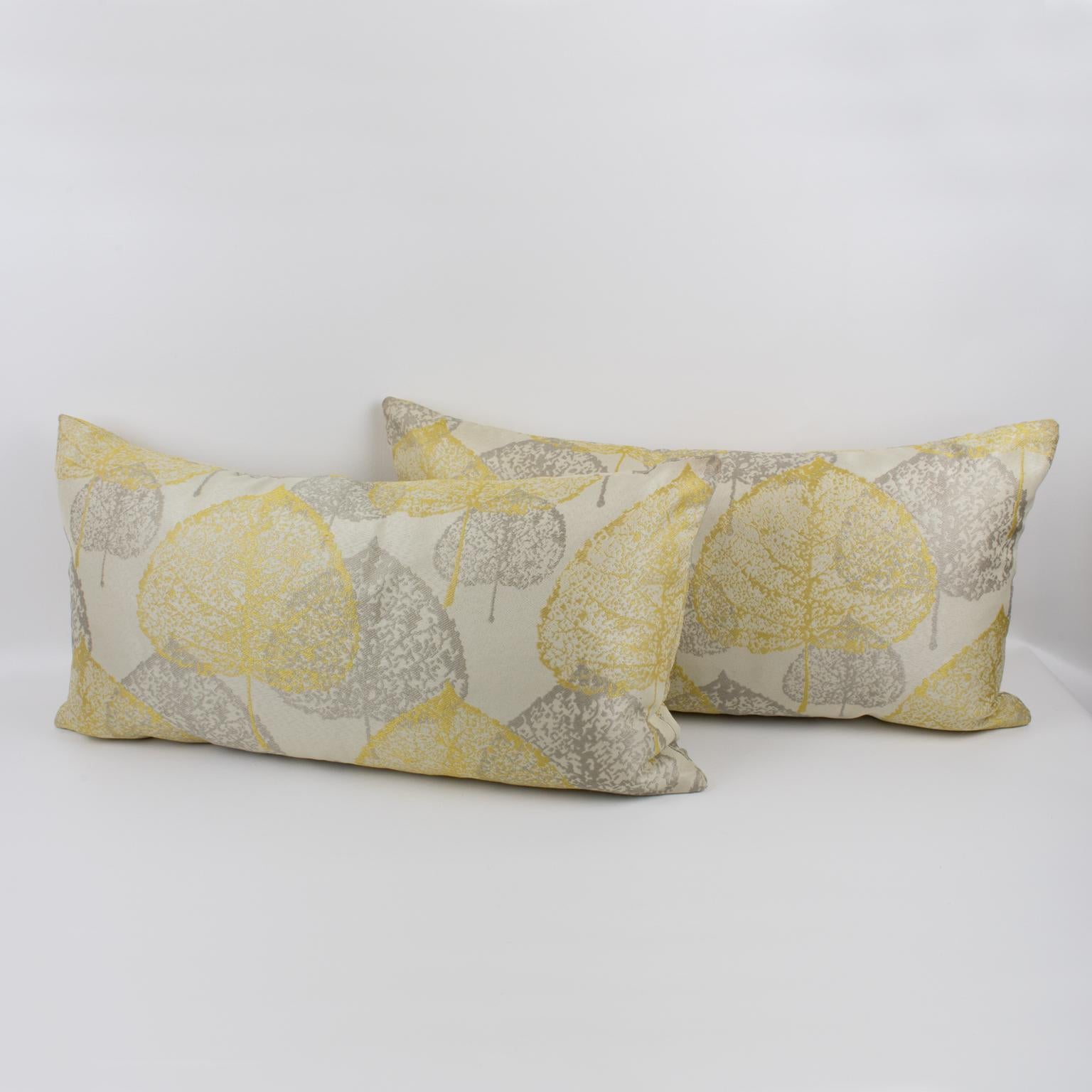 This is a lovely set of two damask throw pillows. These lumbar pillows are covered with a textured naturalist design in silver-gray and light yellow colors over a silky off-white background. A zipper encloses an inner feather pillow. Their