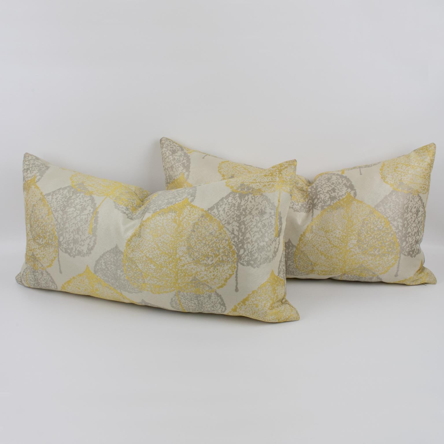 Questo è un delizioso set di due cuscini da lancio damascati. Questi cuscini lombari sono rivestiti con un disegno naturalistico dai colori grigio-argento e giallo chiaro su uno sfondo bianco sporco e setoso. Una cerniera racchiude un cuscino