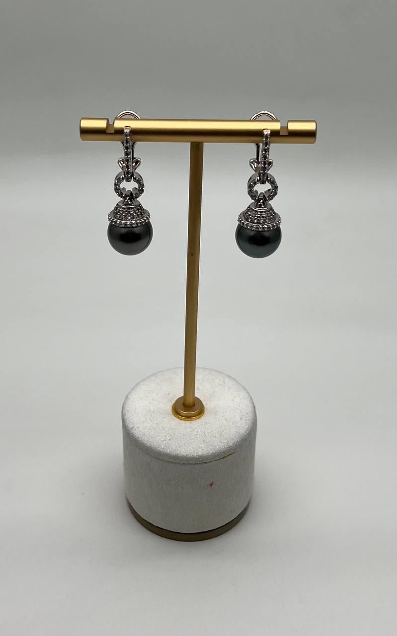 This exquisite pair features intricate white gold detailing with black Tahitian pearls. The earrings showcase a sophisticated design with sparkling diamonds and a graceful drop style. Crafted with precision, they offer a timeless elegance and subtle