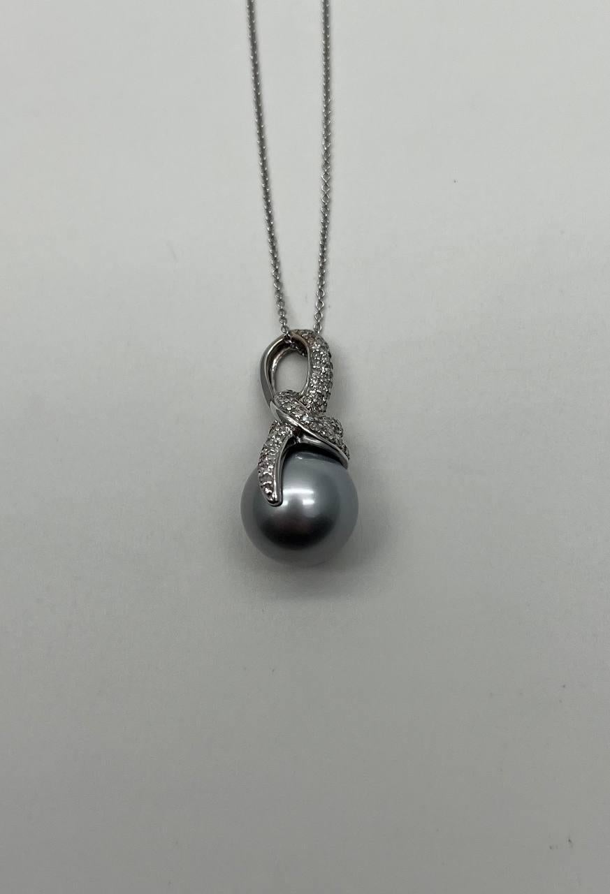 Experience the refined sophistication of this pendant necklace.
This piece features a lustrous grey pearl, elegantly embraced by a swirl of pavé-set diamonds.
The pendant is suspended from a delicate chain, creating a harmonious balance of