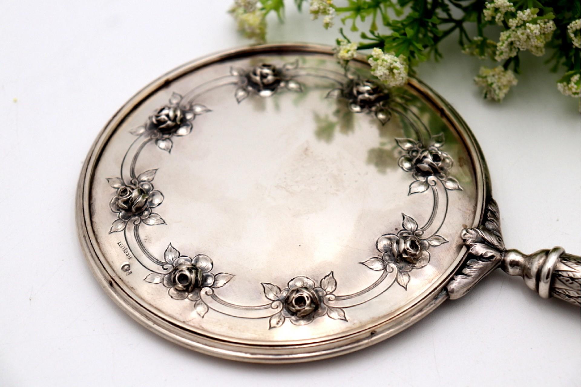 Description: Silver hand mirror with reliefs and rose applications on the back, handle with engravings and friezes. Metal: Silver. Origin: Portuguese. Brand: javali II Title. Weight: 415.17 grams. Dimensions: 13cmx25cm. Content: 833/1000. Assay