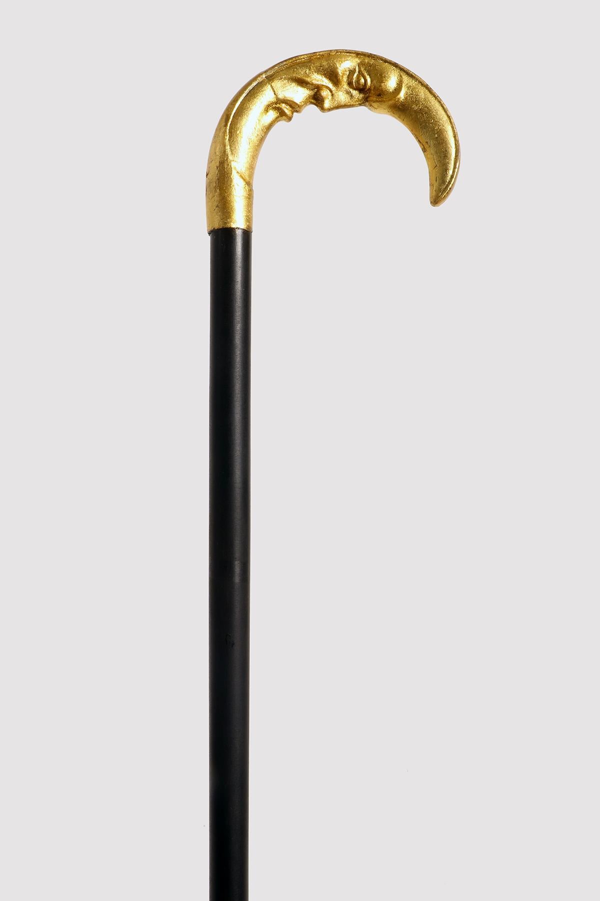 Walking stick: gold foil finished silver knob depicting a crescent moon with a human face. Ebony wood shaft. Metal tip. France circa 1900.