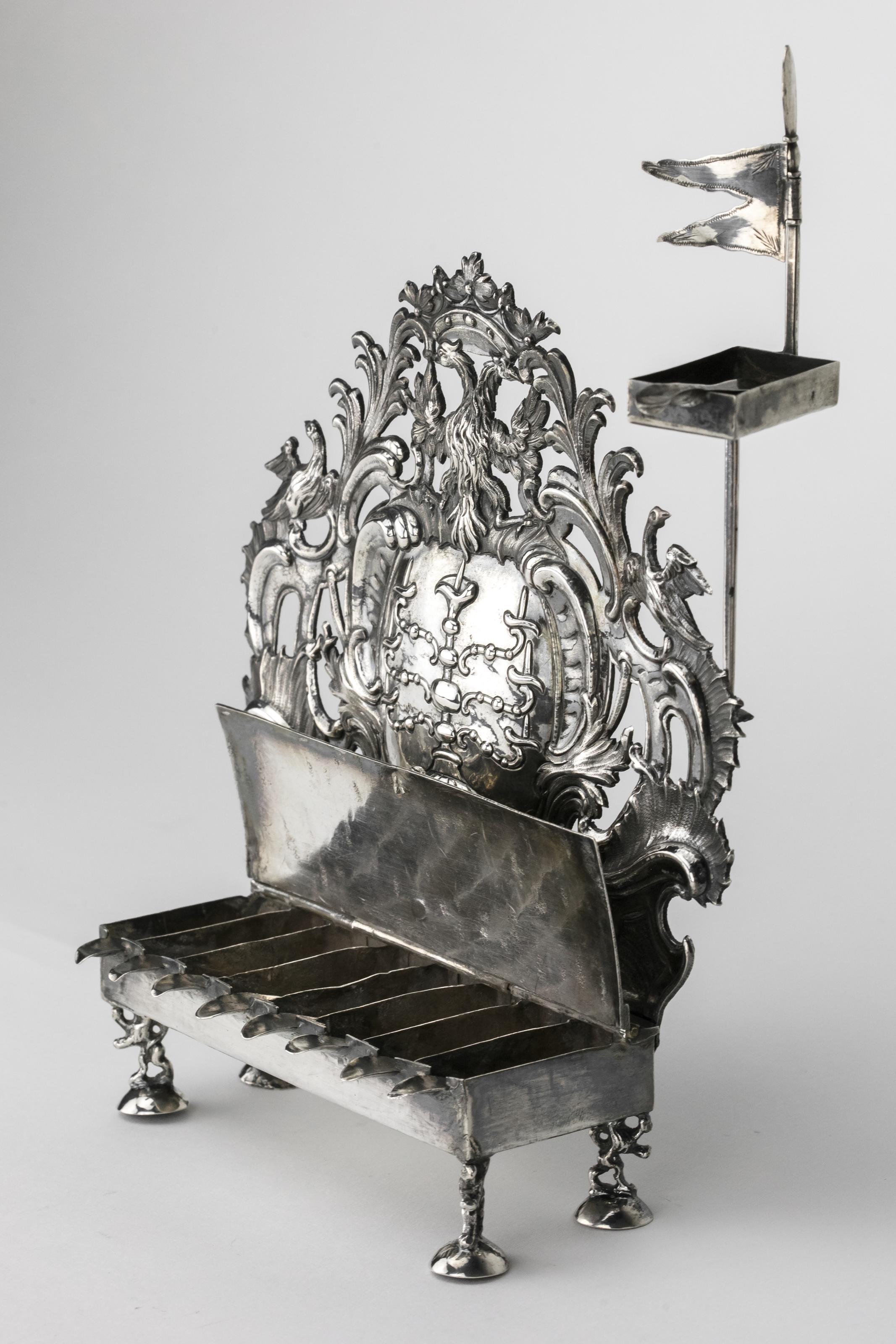 Decorated with Rococo cartouche enclosing a Menorah, the center tooled in a checker pattern by crowned double-headed eagle, supported by four rampant lions, has servant light.
Made in Frankfurt, Germany, between 1748-76, marked on backplate and