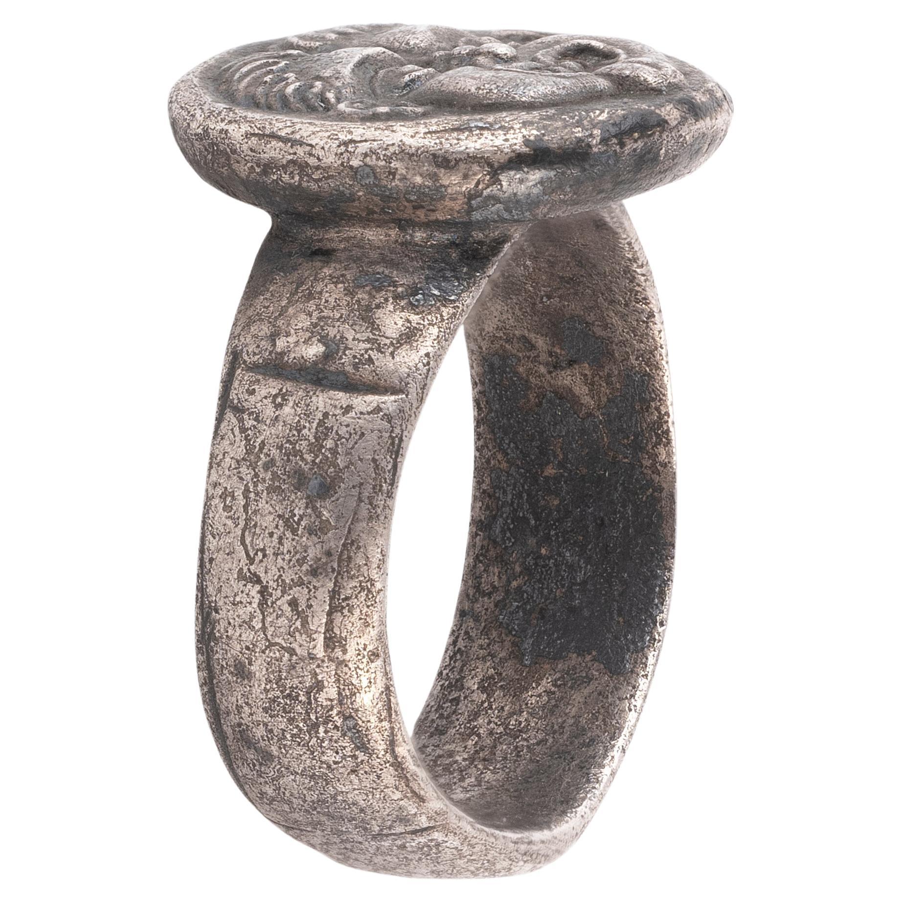 Anillo pesado de plata engastado con una antigua moneda de plata con una cabeza de Gorgona en el anverso y un toro de pie en el reverso. La moneda mide aprox. 14 mm redonda. 
Anillo talla 8,5
Peso: 12,7 gramos. 
Estado: Pyrion, Misia
Denominación: