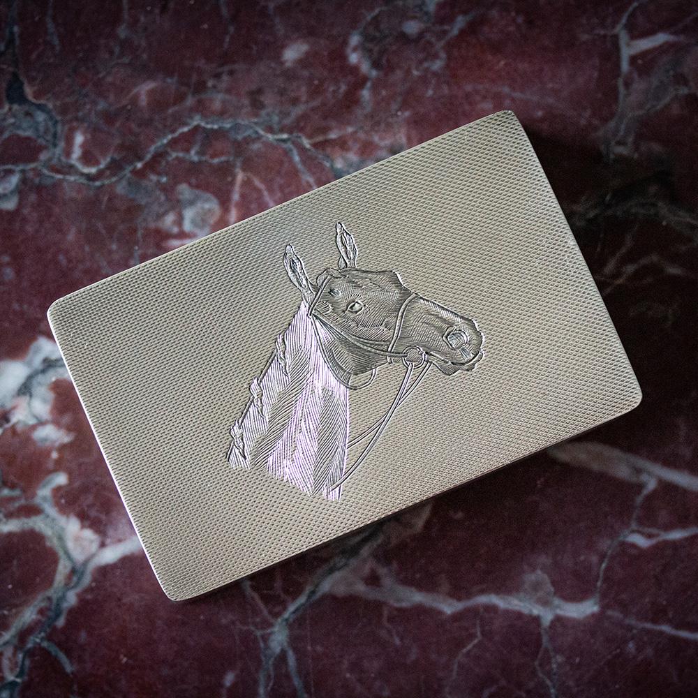 Hallmarked Asprey, London

The case of flat rectangular form with a splayed lid and base featuring a neat engine turned pattern throughout. The lid with a high quality engraved horses head wearing its reigns. When opened the Cigarette Case features