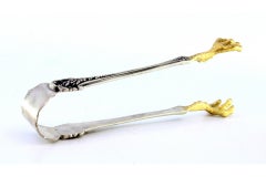 Silver ice tongs in the shape of golden bird claws